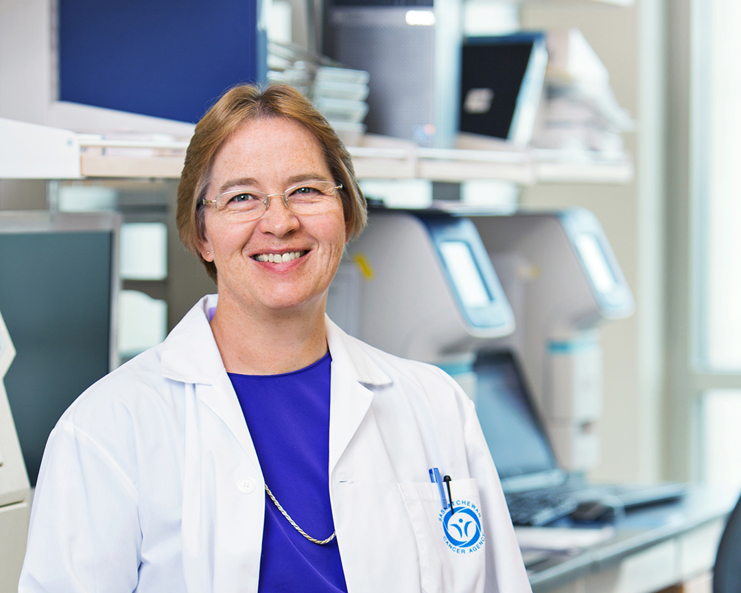 Photo of Dr. Deborah Anderson, wearing a lab coat, in a laboratory at the University of Saskatchewan campus.